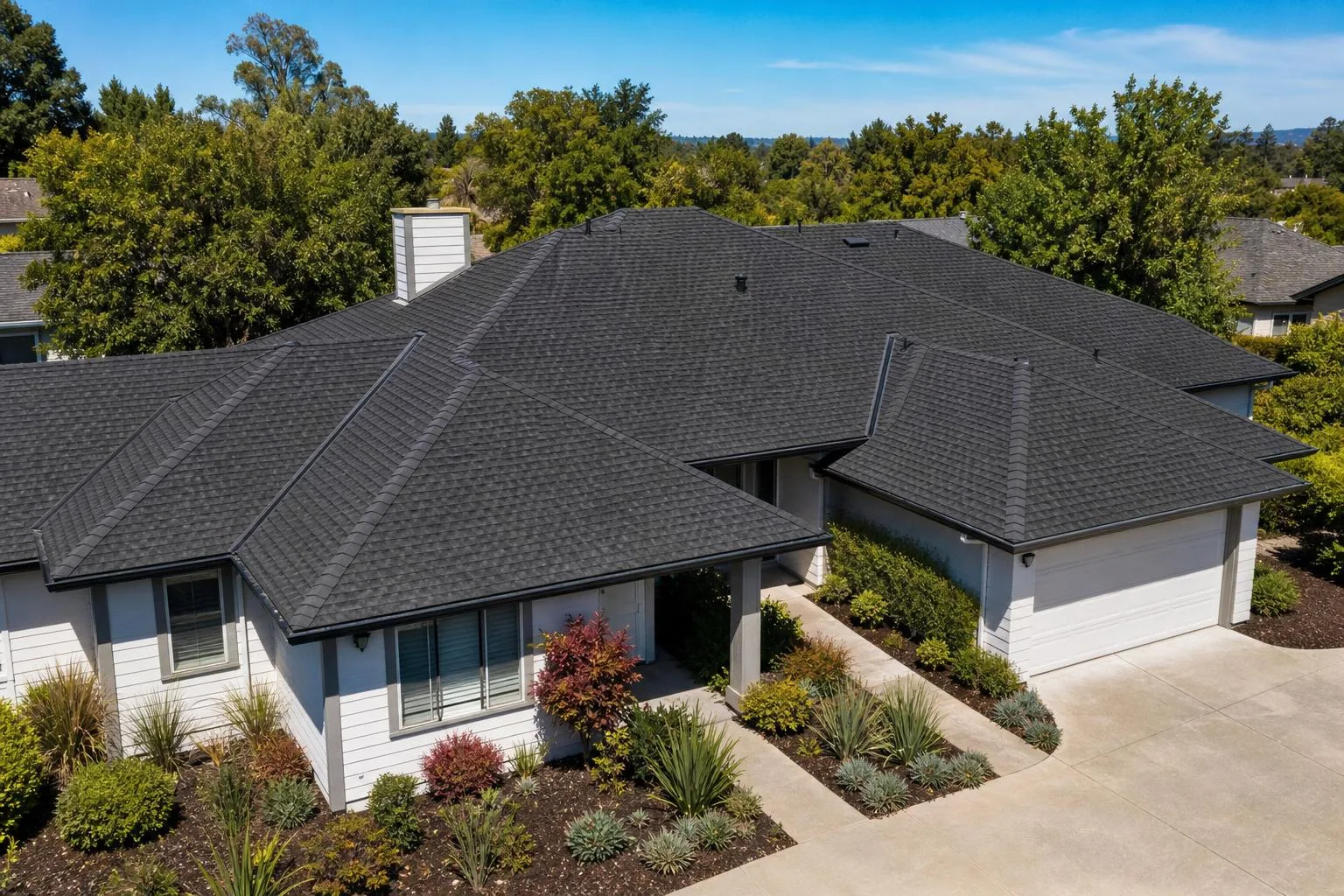 Aerial view of a newly installed architectural shingle roof on a single story Northern California home with clean ridge lines and new gutters