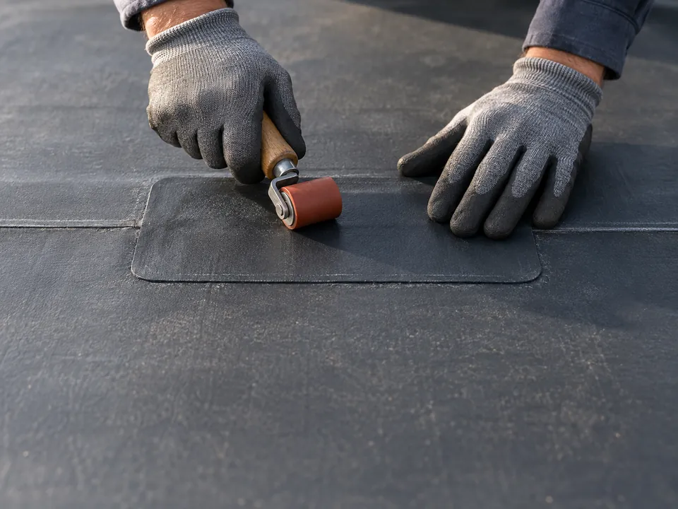 Illustration of a roofer pressing a repair patch onto a commercial roof membrane